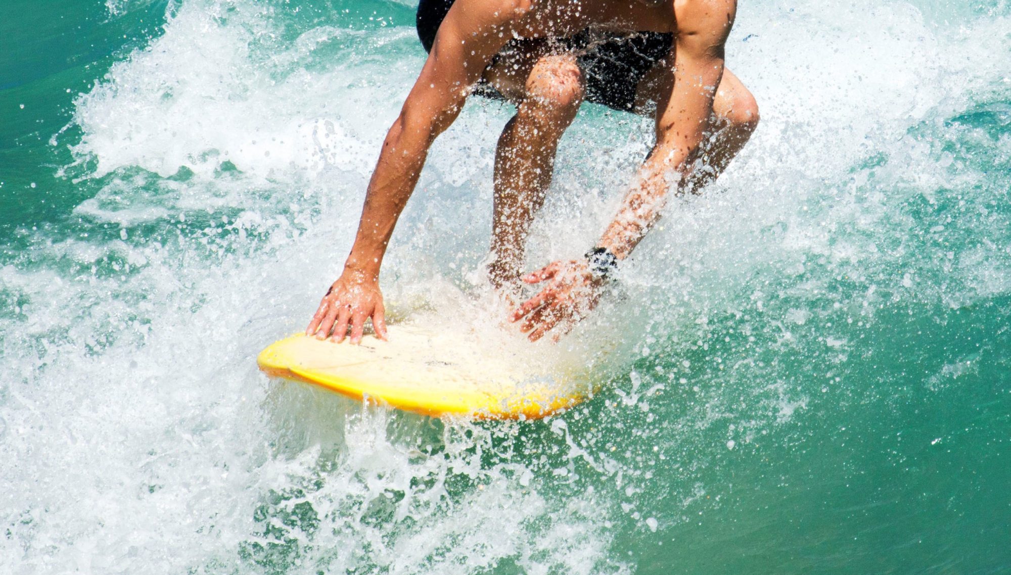 Close-Up ofsStaying low on a surfboard a man riding a wave on a surf board on a body of water