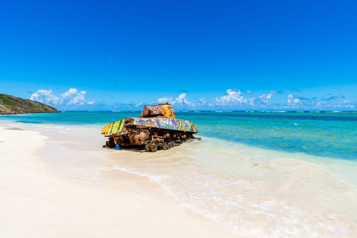 a boat sitting on top of a sandy beach next to the ocean