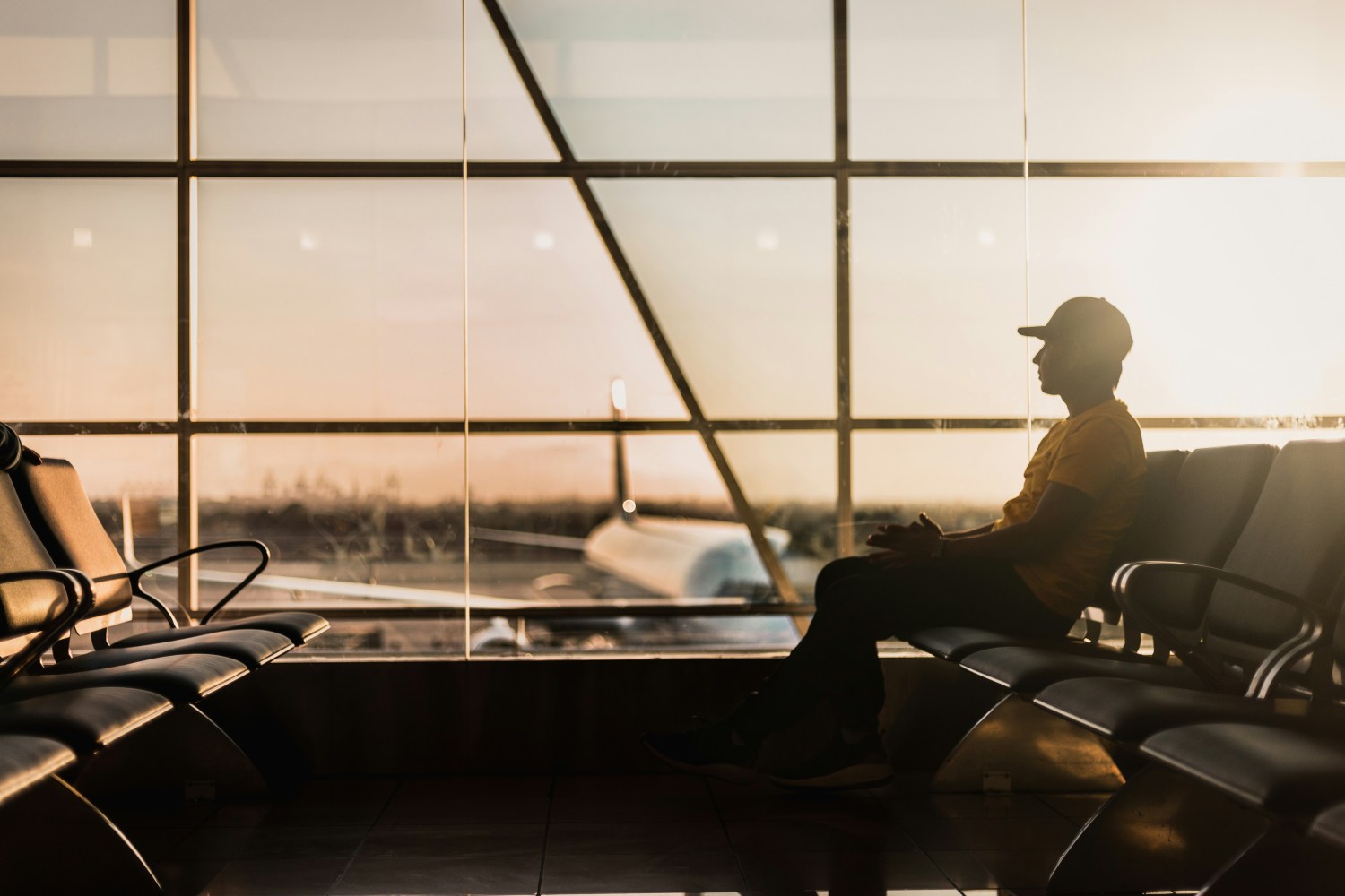 Silhouette of a person sitting in an airport terminal at sunset.