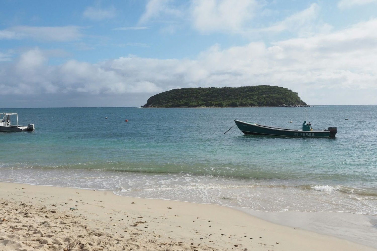 a boat sitting on top of a sandy beach next to the ocean